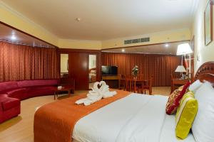 a hotel room with a large bed and a couch at City Palace Hotel in Dubai
