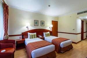 a hotel room with two beds and a chair at City Palace Hotel in Dubai