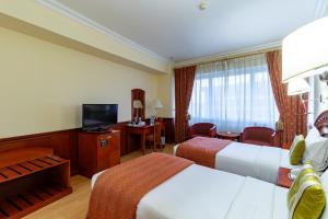 a hotel room with two beds and a television at City Palace Hotel in Dubai