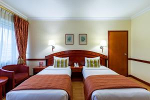 a hotel room with two beds and a chair at City Palace Hotel in Dubai