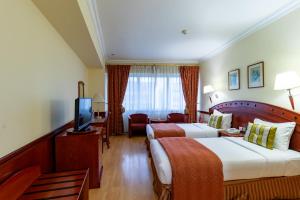 a hotel room with two beds and a television at City Palace Hotel in Dubai