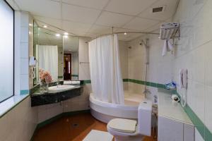 a bathroom with a tub and a toilet and a sink at City Palace Hotel in Dubai