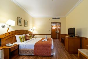 a hotel room with a bed and a flat screen tv at City Palace Hotel in Dubai