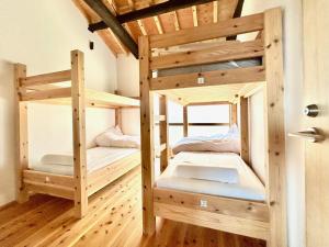 2 łóżka piętrowe w pokoju z drewnianą podłogą w obiekcie kotobukian 寿庵 w mieście Awaji