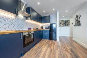 a large kitchen with blue cabinets and wooden floors at 2 - West London Brand New Loft in London