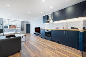 a kitchen with blue cabinets and a living room at 2 - West London Brand New Loft in London