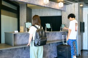 dos personas de pie en un mostrador con su equipaje en COGO TENNOJI en Osaka