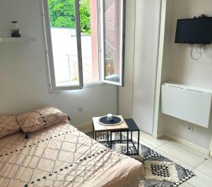 - une chambre avec un lit, une table et une fenêtre dans l'établissement L'Oasis Cosy, à Villeurbanne