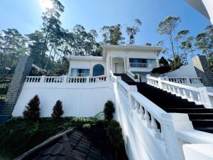 a white house with a white fence and stairs at Skyline BlueDome Villa Ciwidey in Ciwidey
