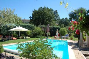 a woman is walking by a swimming pool at La picholine chambre paons in Courry +5 photos