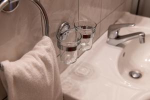 a bathroom sink with two glasses and a towel at Hotel de la Place in Vevey