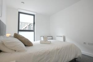 a white bed with a stuffed animal sitting on it at Cosy 1 bed - Heart of Birmingham in Birmingham
