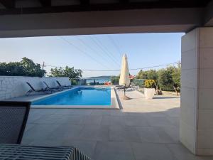 - Piscina con mesa y sombrilla en Holiday house Doris with pool, garden and view, en Kaštela