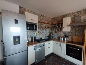 een keuken met witte kasten en een koelkast bij Appartement cosy in Perpignan