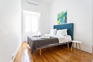 a white bedroom with a bed with a blue headboard at Alagoa Apartments in Tavira