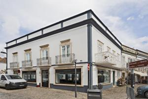 a white building with balconies on a street at Alagoa Apartments in Tavira