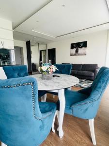 jadalnia ze stołem i niebieskimi krzesłami w obiekcie Dainu street apartament w Szawlach