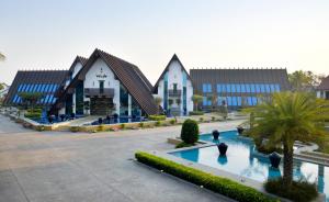 a large building with a pool in front of it at WOODS - Mangalyam Meadows in Valsād