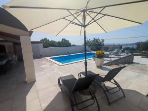 un patio con sombrilla, sillas y piscina en Holiday house Doris with pool, garden and view, en Kaštela