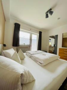 2 camas blancas en un dormitorio con ventana en Ferienwohnung Kircher, en Obermaiselstein