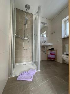 y baño con ducha y toallas púrpuras en el suelo. en Ferienwohnung Kircher, en Obermaiselstein
