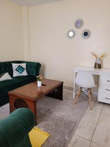 ein Wohnzimmer mit einer grünen Couch und einem Tisch in der Unterkunft Lux Suites Supaboma Apartments Embakasi in Nairobi