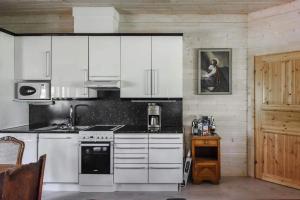 uma cozinha com armários brancos e um fogão em Villa Classic em Ahtari