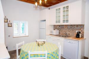 a kitchen with a table and white cabinets and a sink at Quinta Santo António in Pereiro da Palhacana