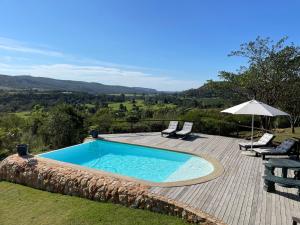 a swimming pool with two chairs and an umbrella at Howberry Hills in Plettenberg Bay