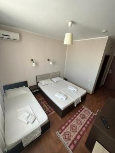 two beds in a room with two rugs at Hotel Promenada in Mamaia