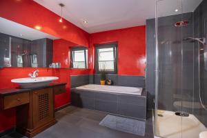een badkamer met rode muren, een bad en een wastafel bij Chalet Rosenweg in Fügen