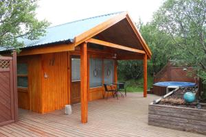 een houten terras met een paviljoen met een tafel bij Relaxing and cozy cottage with hot tub in Húsafell