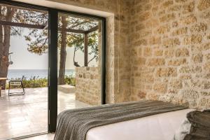 a stone walled bedroom with a bed and a view of the ocean at Home By The Sea in Kardamili