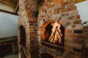 a brick fireplace with a fire in it at Casa Florea Stanceni in Ciobotani