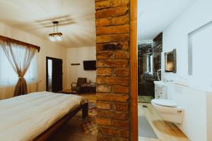 1 dormitorio con cama y pared de ladrillo en Casa Florea Stanceni en Ciobotani