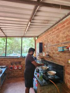 Nebula Nest Cafe & Hostel في أورفيلا: امرأة تقف في مطبخ تقوم باعداد الطعام