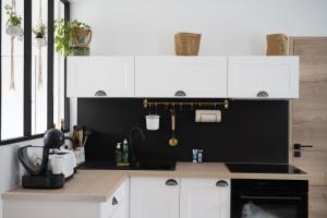 eine Küche mit weißen Schränken und einer schwarzen Wand in der Unterkunft L'AuthentiK in Guingamp