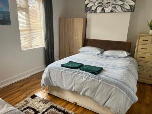 een slaapkamer met een bed met twee groene handdoeken erop bij TownHouse near Beach Bournemouth in Bournemouth