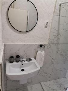 La salle de bains blanche est pourvue d'un lavabo et d'un miroir. dans l'établissement CALLA 4 Apartment - Main Square, in the City Shopping Center - PARKING SLOT WITH SECURITI AND VIDEO CAMERA, à Skopje
