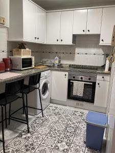 uma cozinha com armários brancos, um fogão e uma máquina de lavar louça em La Lúnula by Twelve Apartments VUT3392AS em Gijón