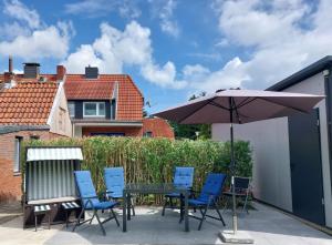 eine Terrasse mit einem Tisch, Stühlen und einem Sonnenschirm in der Unterkunft Voslapper Seeluft in Wilhelmshaven