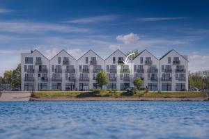 a large white apartment building next to a body of water at Hafenkoje in Olpenitz