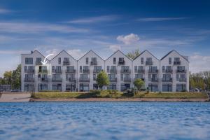 a large white apartment building next to a body of water at Enjoy in Olpenitz