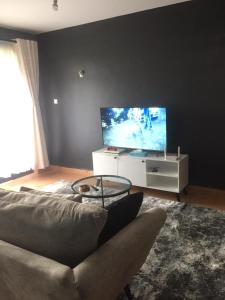 ein Wohnzimmer mit einem Sofa und einem Flachbild-TV in der Unterkunft Family-Friendly Home in Nairobi