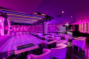 a purple nightclub with pink chairs and a bar at City Palace Hotel in Dubai