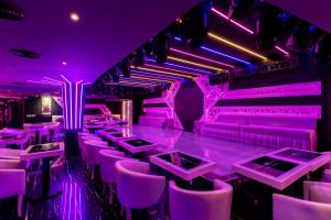 a nightclub with purple lighting and tables and chairs at City Palace Hotel in Dubai
