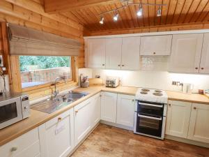 a kitchen with white cabinets and a sink and a stove at 64 Acorn Lodge Kenwick Park in Louth