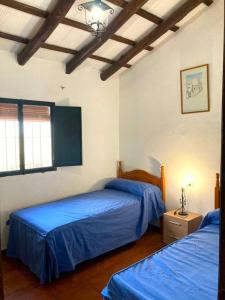 2 camas en una habitación con sábanas azules en Finca Villa Coral, en Cazalla de la Sierra