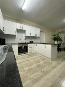a large kitchen with white cabinets and a table at Cleo's Corner in East London