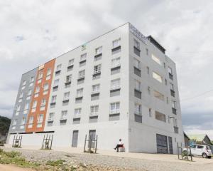 un hombre sentado frente a un edificio blanco en Shalom Studio city Apartments., en Naivasha